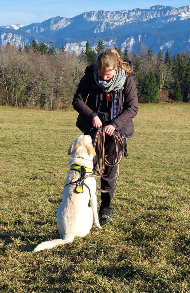 Une éducatrice comportementaliste canine en méthode positive qui s'apprête à donner une friandise au chien.